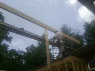 Carpenter setting a ridge beam over a new addition frame — Ice Dam Removal by Roofing Brothers in Basin