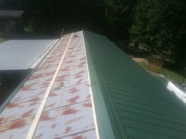 Old rusted panels beside newly installed green metal roofing — Wind Damage Roof Repair by Roofing Brothers in Basin