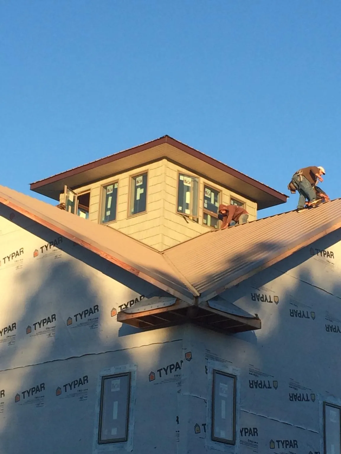 Roofers working around a rooftop cupola on a new metal roof at sunset — Roof Waterproofing in Basin by Roofing Brothers